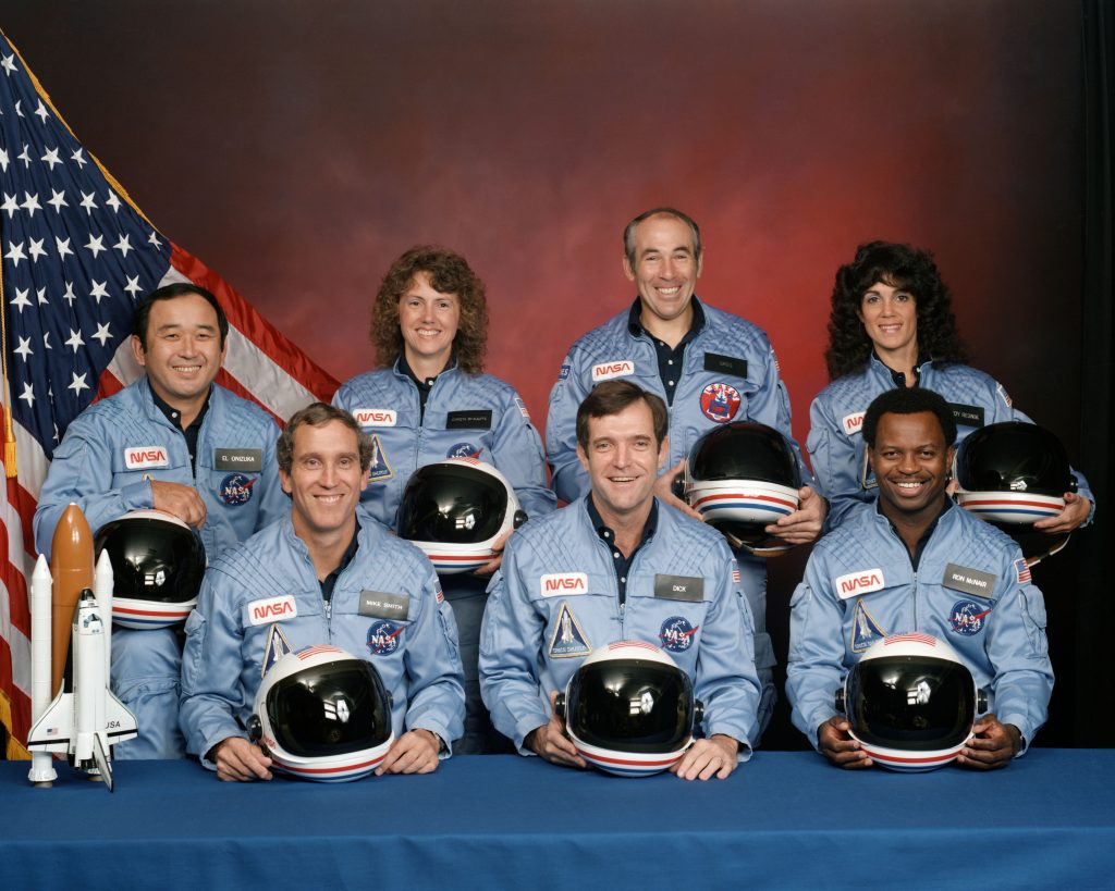 The STS-51L crewmembers are: in the back row from left to right: Mission Specialist, Ellison S. Onizuka, Teacher in Space Participant Sharon Christa McAuliffe, Payload Specialist, Greg Jarvis and Mission Specialist, Judy Resnik. In the front row from left to right: Pilot Mike Smith, Commander, Dick Scobee and Mission Specialist, Ron McNair.